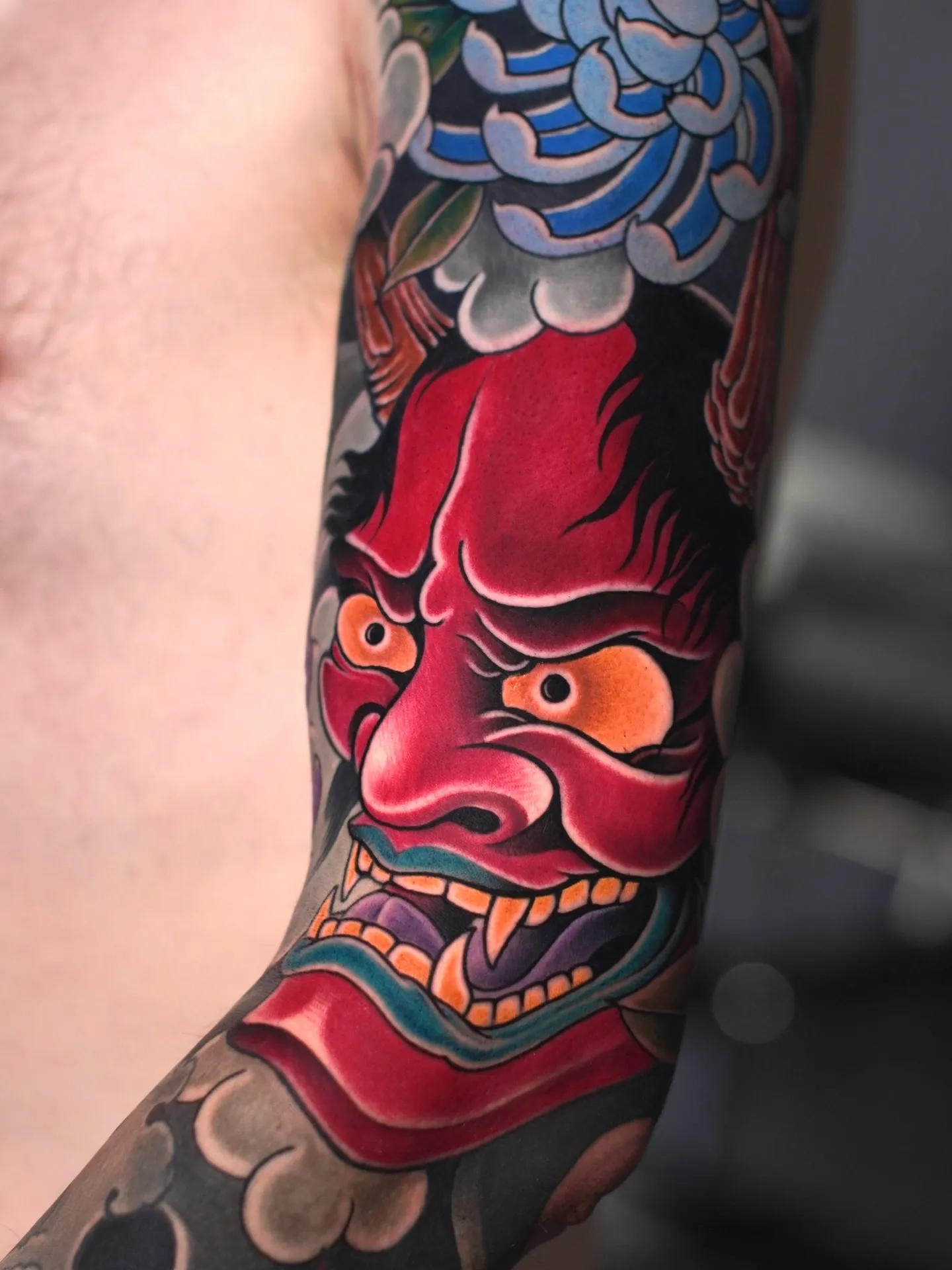 Japanisches Tattoo in Farbe: rote Hannya-Maske mit blauer Chrysantheme