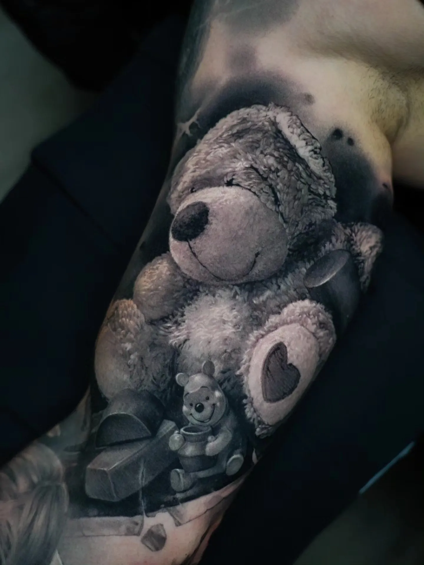 Fotorealistisches Schwarz-Grau-Tattoo: Plüsch-Teddybär mit Herz-Pfote